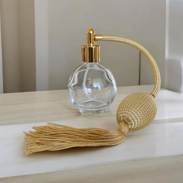 round bottle dressing table perfume atomizer with gold tassel pump on surface