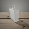 Clear glass bottle on a wooden surface with a gray background