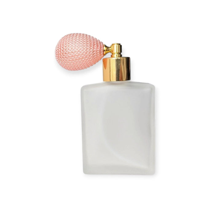 Perfume bottle with pink bulb atomizer and gold nozzle on a white background