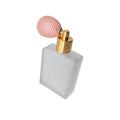 Perfume bottle with a pink bulb spray and gold nozzle on a white background