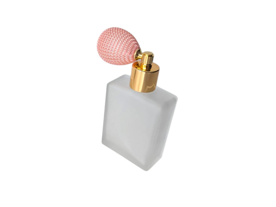 Perfume bottle with a pink bulb spray and gold nozzle on a white background